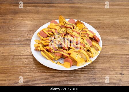 Ration de patatas bravas avec des saucisses frites en tranches et beaucoup de sauce épicée sur le dessus Banque D'Images