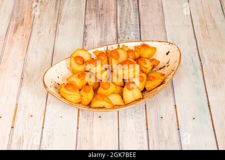 Populaire tapa espagnol de sauce chaude patatas bravas servi dans un bol blanc avec rebord doré Banque D'Images