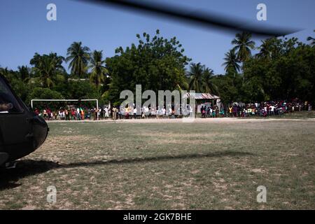 Les habitants de la communauté d'Anse au veau, en Haïti, attendent les gardes de la Garde nationale de l'armée de Porto Rico qui déchargent les provisions alimentaires de l'hélicoptère UH-60, le 24 août 2021. Banque D'Images