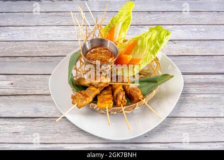 Brochettes de poulet grillé de style thaïlandais avec un bol de sauce épicée à tremper sur une feuille de banane Banque D'Images