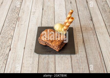 Ration de gâteau au chocolat au brownie avec glace à la vanille et galette de biscuit sur plaque d'ardoise noire Banque D'Images