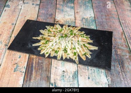 Plateau en ardoise noire avec anchois marinés avec persil et ail pour servir de tapa dans un restaurant espagnol Banque D'Images