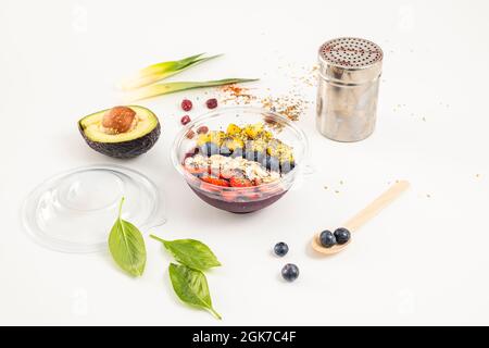 Un bol d'açai avec des baies, des amandes, des bleuets, de la mangue et de la pâte de cacao dans un récipient de livraison à domicile Banque D'Images