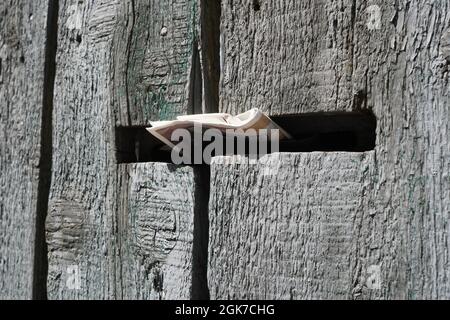 Ancienne clôture rustique en bois naturel robuste avec boîte aux lettres attachée à elle et brochure publicitaire dans la boîte aux lettres Banque D'Images