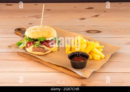 Hamburger de bœuf galicien au jambon de jabago, beaucoup de fromage fondu et de pousses de laitue d'agneau garnies de frites et de sauce barbecue Banque D'Images