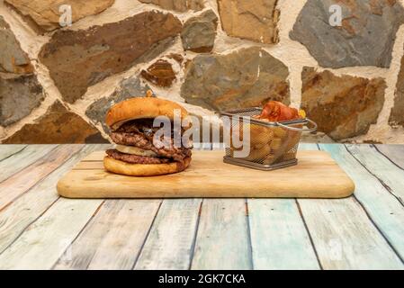 Double hamburger de bœuf grillé au fromage de chèvre, oignons confits, bacon frit et frites Banque D'Images