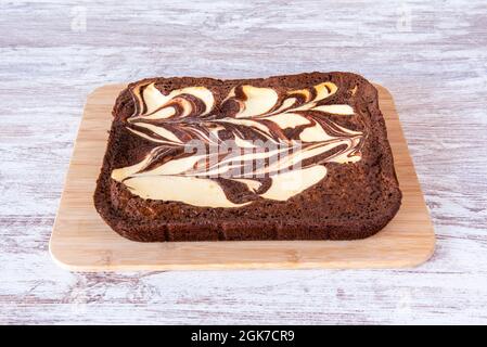 Tarte au brownie au cheesecake entier sur une table en bambou et une table blanche. Banque D'Images