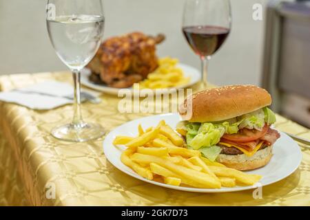 Hamburger classique sur un menu d'été avec poulet rôti et frites. Hamburger de bœuf au cheddar, bacon frit, tomate et laitue, ketchup et moutarde Banque D'Images