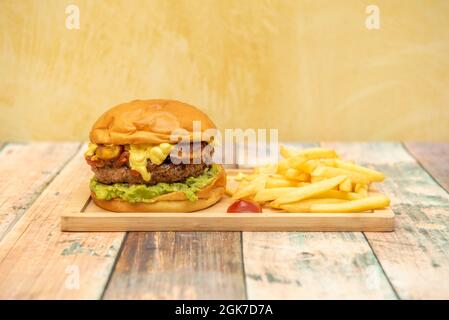 Double hamburger mexicain avec guacamole, cheddar et jalapeños garni de frites, ketchup et moutarde Banque D'Images