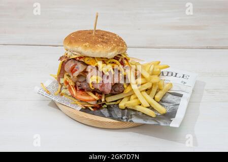 Double hamburger de bœuf, avec beaucoup de bacon, œuf frit, fromage fondu, oignon et tomate avec ketchup et moutarde et frites Banque D'Images