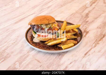 Hamburger de bœuf avec sauce végétale et fromage fondu, œuf et frites sur une table en marbre Banque D'Images