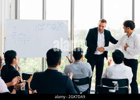 Caucasian business manager présente la nouvelle Asian businessman in front of séminaire réunion avec de nombreux employés de bureau de l'entreprise configuration d'écoute Banque D'Images