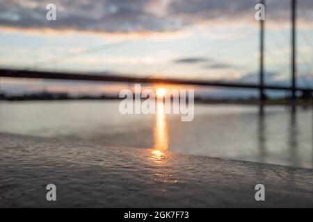 Vue macro au soleil sur la surface et défoqué du Rhin, pont et ciel de coucher du soleil. Banque D'Images