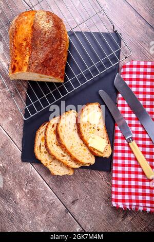 Pain artisanal fraîchement cuit au levain et au fromage, posé sur une grille de refroidissement métallique sur une table en bois Banque D'Images