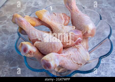 Fermer les cuisses de poulet crues dans un bol en verre. Pilons de poulet non cuits. Banque D'Images