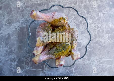 Cuisses de poulet crues mélangées à diverses épices. Des pilons de poulet non cuits sont préparés pour être cuits. Banque D'Images