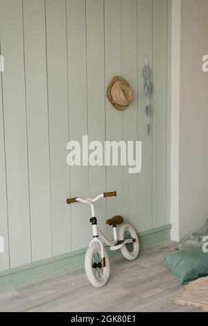 Vélo blanc pour enfants de petite taille près d'un mur en bois clair dans la maison Banque D'Images