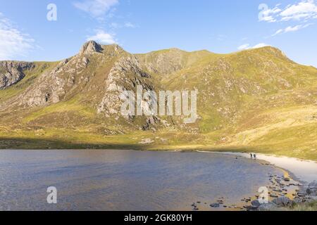 Llyn Idwal, Snowdonia, Royaume-Uni, 8 septembre 2021: Deux personnes marchant le long de la plage de galets de Llyn Idwal avec les rochers de Castell y Geifr derrière. Banque D'Images