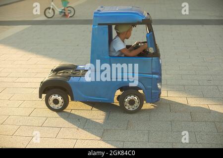 Voiture électrique pour enfants. Un petit camion pour un enfant. Une voiture bleue conduite par un présélectionneur. Banque D'Images