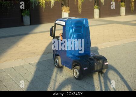 Voiture électrique pour enfants. Un petit camion pour un enfant. Une voiture bleue conduite par un présélectionneur. Banque D'Images