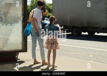 Les gens à l'arrêt de bus. En attente de transport. Les gens se tiennent devant la route en été, attendant le bus. Banque D'Images