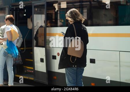 Les gens à l'arrêt de bus. En attente de transport. Les gens se tiennent devant la route en été, attendant le bus. Banque D'Images