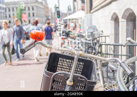 Scène de rue floue avec vélo avec panier et sonnerie de référence contre la rambarde et les personnes défocampées en arrière-plan Banque D'Images