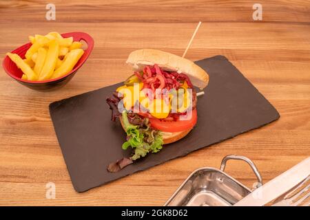 délicieux hamburger de bœuf au fromage cheddar, tranches de bacon frites, tomates en tranches, tranches de jalapeño et laitue en chêne Banque D'Images