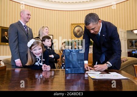 Le président Barack Obama signe des souvenirs pour le mois de mars des dix 2013 l'ambassadrice nationale Nina Centofanti, 8 ans, au bureau de Resolute lors de sa visite au bureau ovale, le 26 mars 2013. Les parents de Centofanti Vince et Christine, le frère Nicholas, et la sœur Mia, non visibles, se tiennent derrière elle. (Photo officielle de la Maison Blanche par Pete Souza) cette photo officielle de la Maison Blanche est disponible uniquement pour publication par les organismes de presse et/ou pour impression personnelle par le(s) sujet(s) de la photo. La photographie ne peut être manipulée d'aucune manière et ne peut pas être utilisée dans des m commerciaux ou politiques Banque D'Images