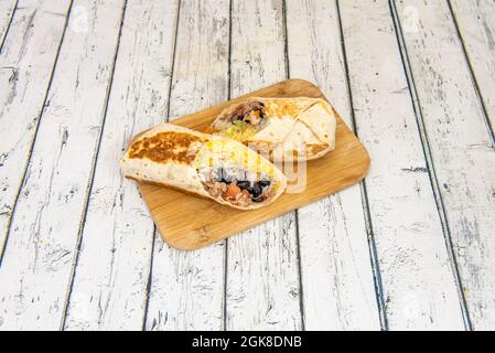 Tortilla burrito de blé grillé mexicain avec porc tiré, haricots noirs, riz et fromage cheddar Banque D'Images
