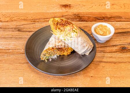 Burrito mexicain de tacos al pasteur avec sauce trempée enveloppée dans une tortilla de blé Banque D'Images