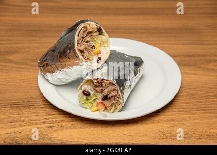 Burrito de bœuf mexicain avec riz, haricots noirs, maïs doux et laitue enveloppée de feuille Banque D'Images