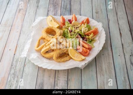 Tapa espagnol de calmar pané avec salade de laitue et de tomate et quartiers de citron sur l'assiette blanche Banque D'Images