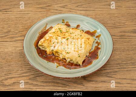 Portion de cannelloni de pâtes farcies avec un ragoût de merlu de Cantabrian avec du fromage râpé gratiné à la sauce soja Banque D'Images