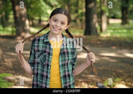 Fille scout mignon braides porter des vêtements à carreaux nature fond, concept de camping Banque D'Images