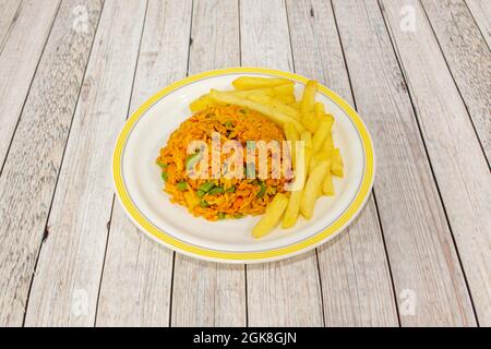 Riz au poulet et légumes sautés, garni de pommes de terre frites sur une assiette blanche et un bord jaune Banque D'Images