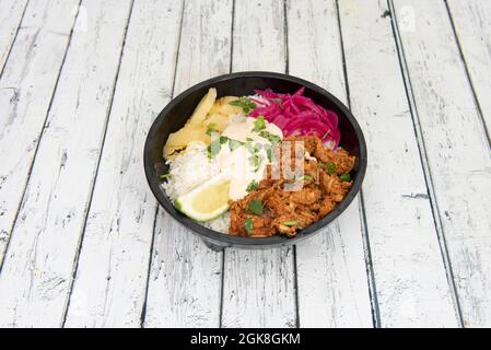 Bol de pibil de cochinita mexicain avec yucca frit et riz blanc. Ragoût de poulet, de lime et de coriandre râpé avec oignon violet conservé. Banque D'Images