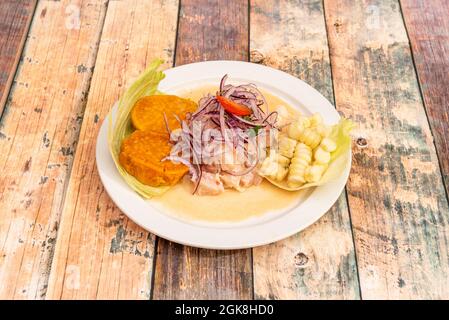 Corvina ceviche de style péruvien avec des tranches de pommes de terre douces et des grains de maïs sur une assiette blanche Banque D'Images