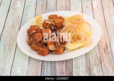 Chicharron de porc frit avec un oignon cuit et yucca frit de style dominicain avec du citron Banque D'Images