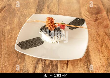 Calmar dans son encre avec tempura de tentacules, riz blanc et tomate rôtie sur une assiette blanche (chipirones en su tinta) Banque D'Images