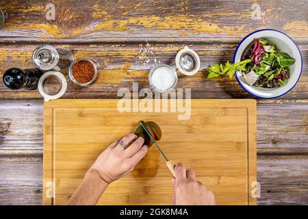 Vue de dessus image des mains de chef féminin avec anneau coupant une tomate sur une table de bambou pour préparer une salade d'été Banque D'Images