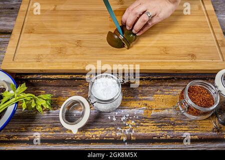 Le chef hache une tomate kumato pour préparer une salade avec des flocons de sel de mer, du paprika et du céleri sur une planche de bambou Banque D'Images