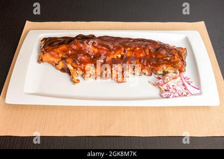 Côtes de porc super tendres marinées avec une sauce barbecue et de la coleslaw sur une assiette blanche Banque D'Images