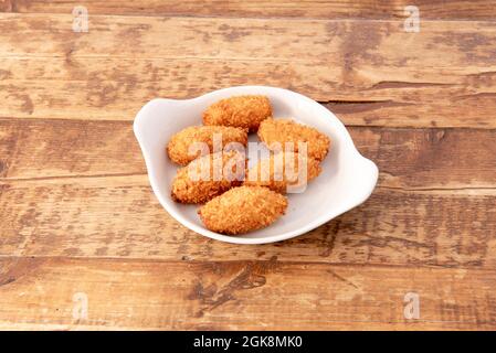 Il sert des croquettes de jambon ibérique dans un bar à tapas espagnol doté de tables en bois rustiques Banque D'Images