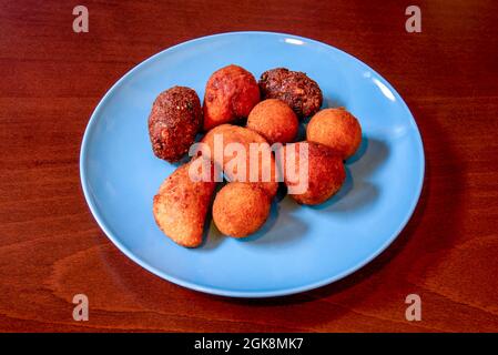 Assiette bleue avec croquettes de différentes saveurs et formes sur table en bois rougeâtre Banque D'Images