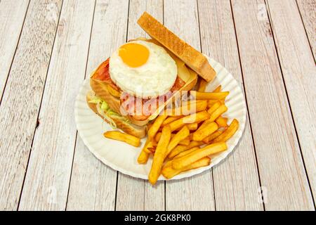 Sandwich à double étage avec œuf frit et jaune pour faire trempette, pain grillé au beurre, tranches de fromage, bacon frit et frites au lettu Banque D'Images