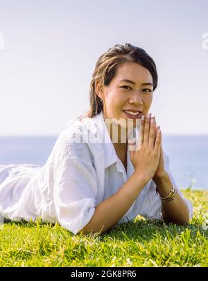 Vue latérale d'une jeune gaie longue cheveux brune dans chaleureux pull-over tricoté sur la main courante et riant heureux tout en appréciant jour d'automne ensoleillé en f Banque D'Images