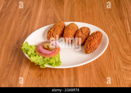 Proportion de croquettes crémeuses pour le restaurant de tapas avec un hors-d'œuvre de salade sur un plateau blanc Banque D'Images