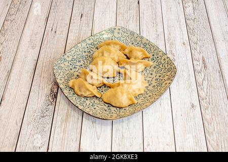 Boulettes chinoises farcies de légumes faits sur le gril et présentées dans une belle assiette avec un motif bleu sur une table blanche Banque D'Images