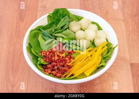 Bol de livraison à domicile avec salade de boules de melon, lanières de poivre jaune, tacos au jambon serrano frits et base d'épinards Banque D'Images